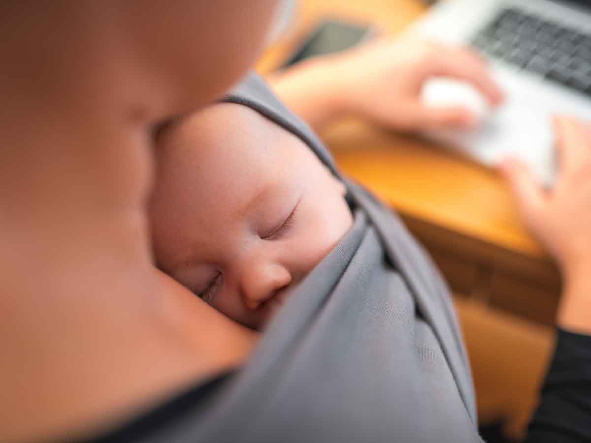 Mama przed komputerem ze swoim maluszkiem w chuście