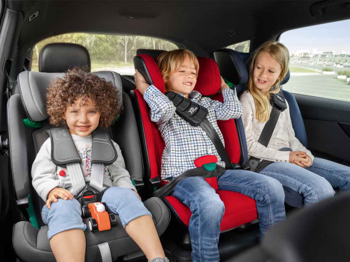 trójka dzieci w samochodzie w fotelikach na tylnej kanapie.