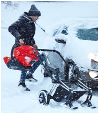 Ojciec przekłada fotelik do samochodu podczas opadów śniegu